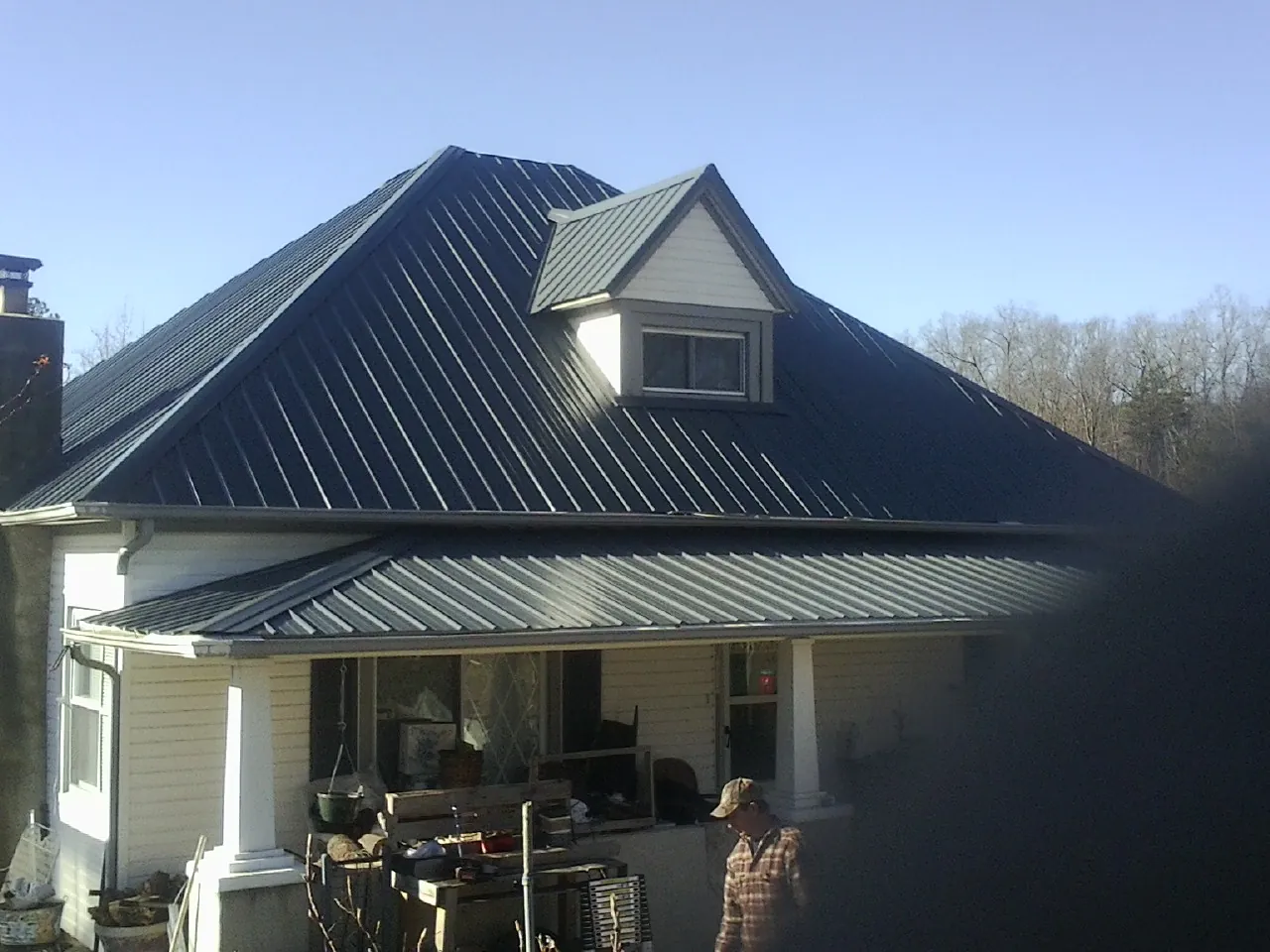 Dark blue standing seam metal roof with a dormer above a front porch in Avoca