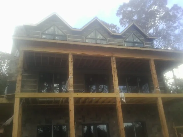 Dormers and porch framing on a large log home under construction — Roof Coating work by our crew in Avoca