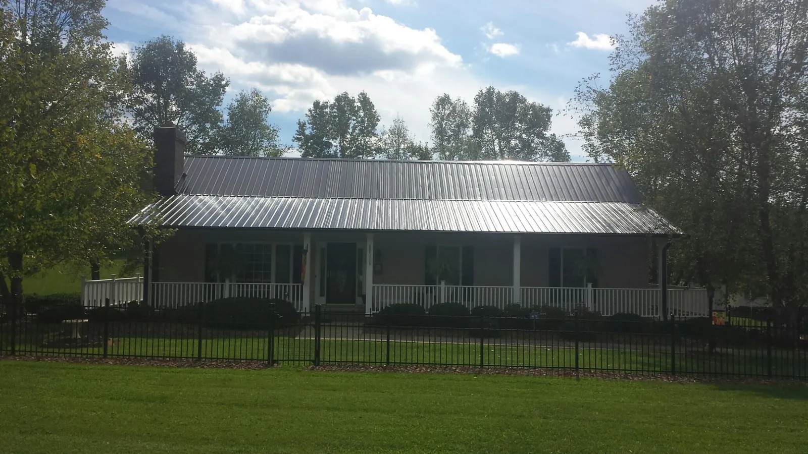Gray metal roof on a brick ranch with a full width front porch — Gutter Guard Installation work by our crew in Avoca